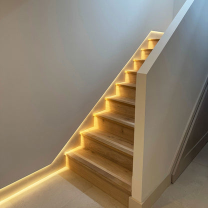 Wooden staircase with built-in lighting against a white wall